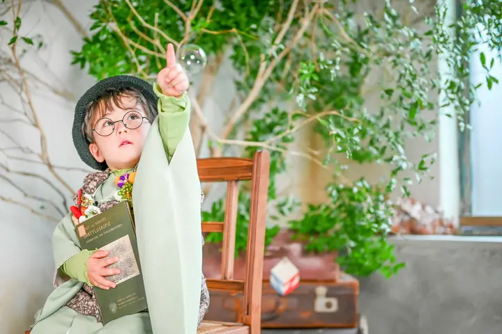 丸メガネと帽子の男の子がシャボン玉を指さす