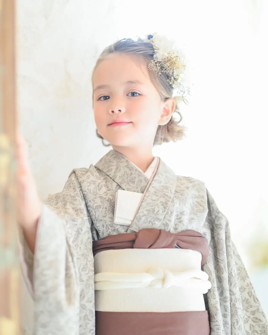 グレーの着物の女の子が窓辺に手をかけて立つ
