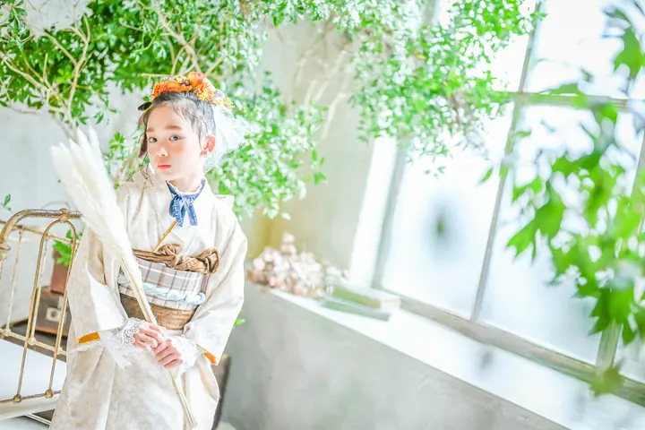 生成りの着物にオレンジの花飾りの女の子がパンパスグラスを抱える