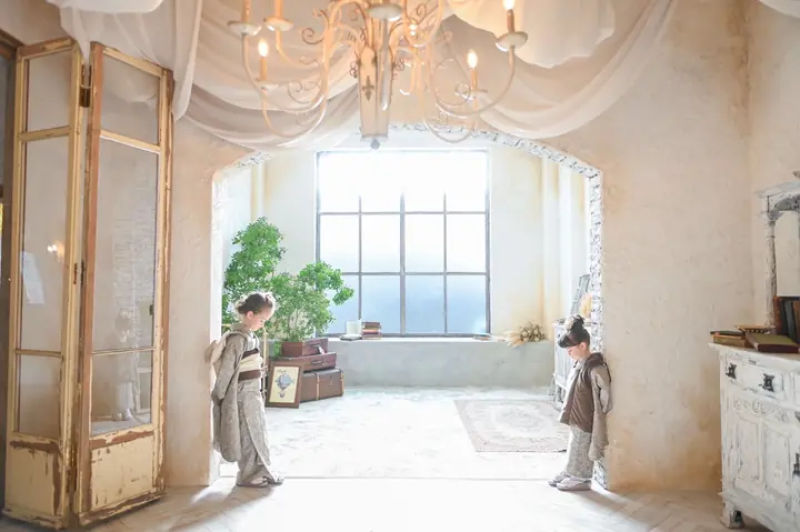 シャンデリアの部屋に立つ着物姿の姉妹