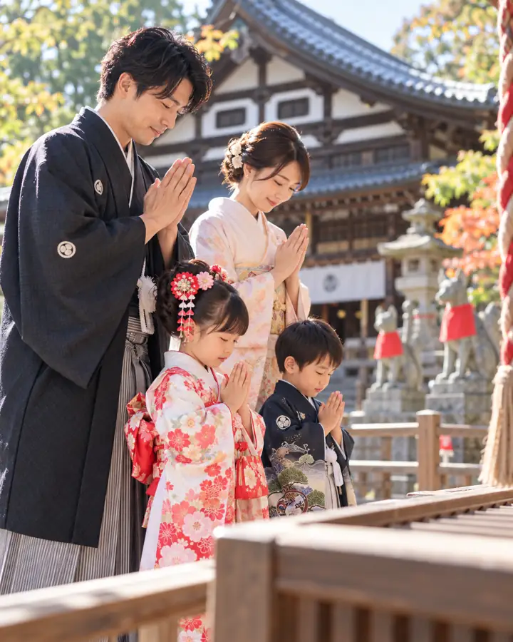 着物姿の家族が神社で手を合わせてお参りする様子